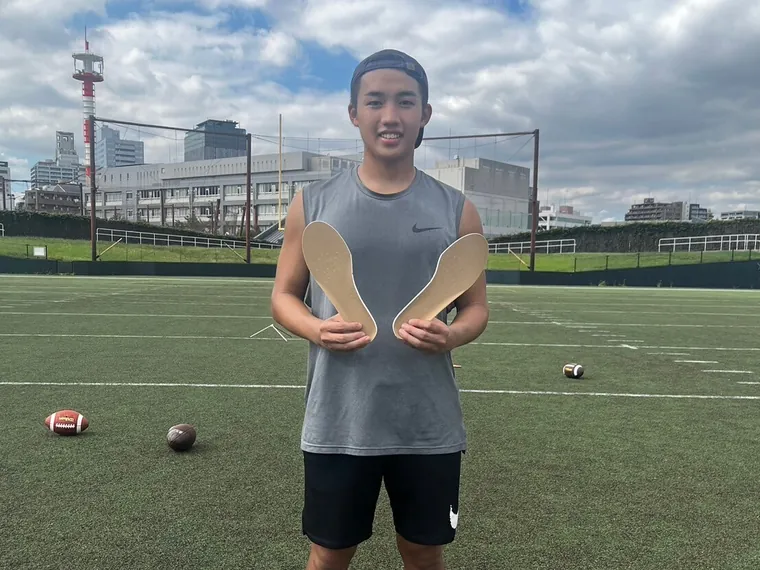 グラウンドでインソールを手にする選手