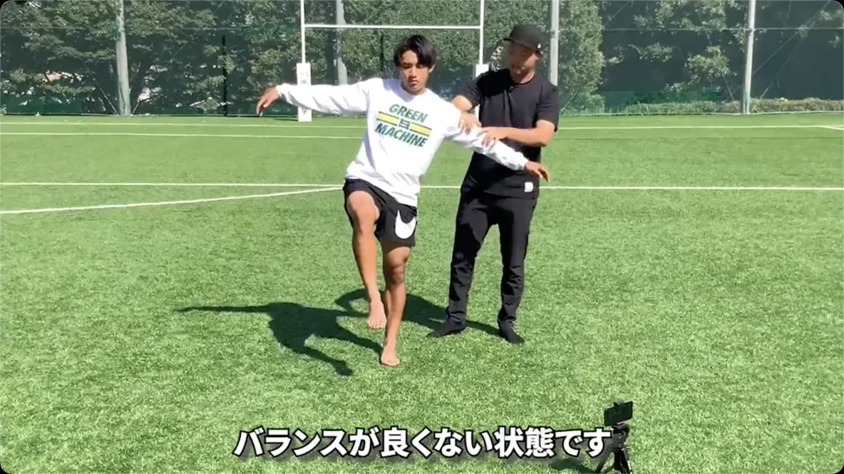 肩を押されて、片足立ちのバランスを崩している選手